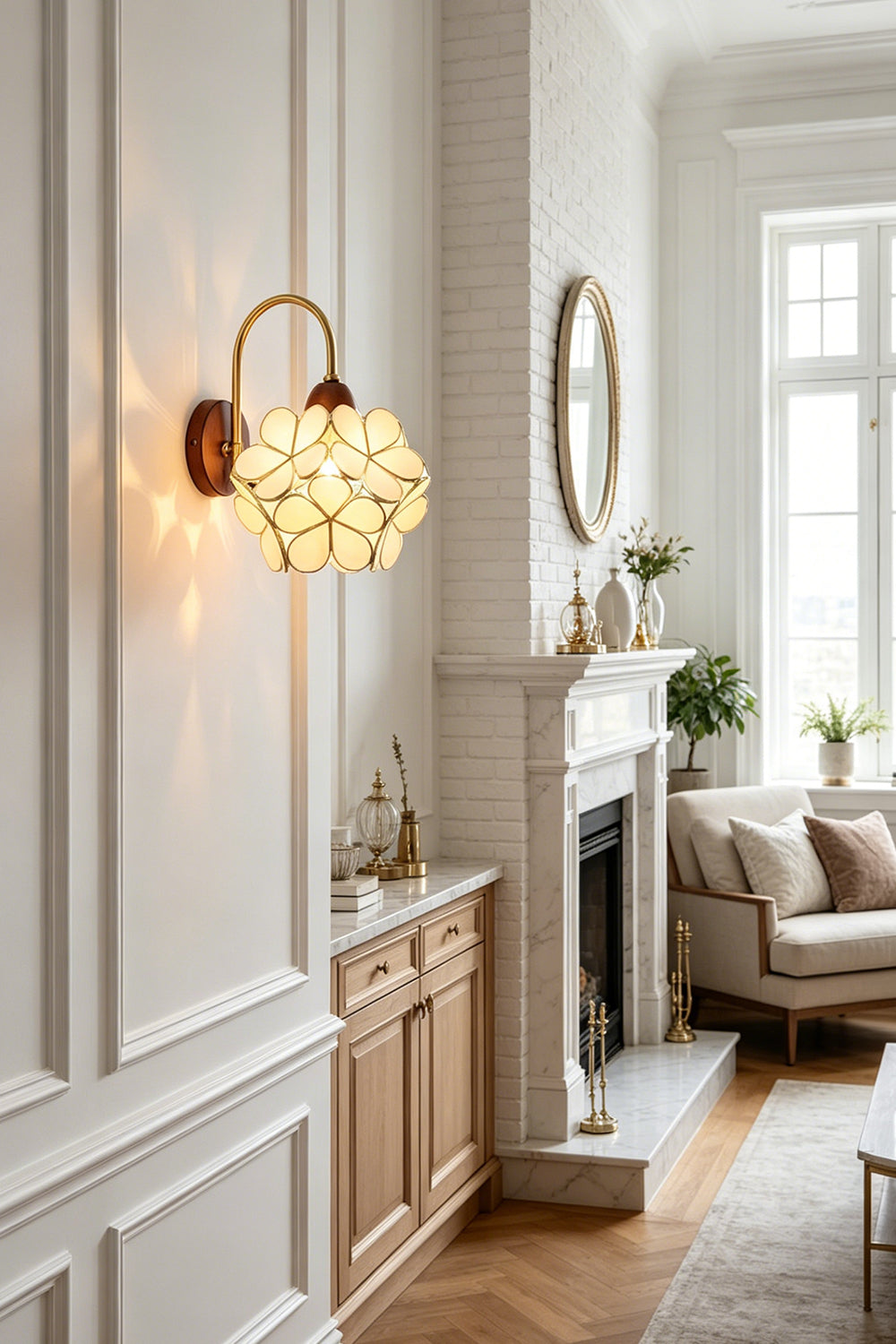 Rosalind Petal Glass Botanical Wall Lamp | Glass, Metal, Wood | Close-up view of the glowing floral sconce throwing soft warm light on a white wall near a fireplace mantel | vexa lamps