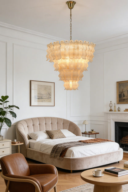 Grand ruffled tiered chandelier | Metal | Glass | Installed in a luxury bedroom above a tufted headboard | vexa lamps