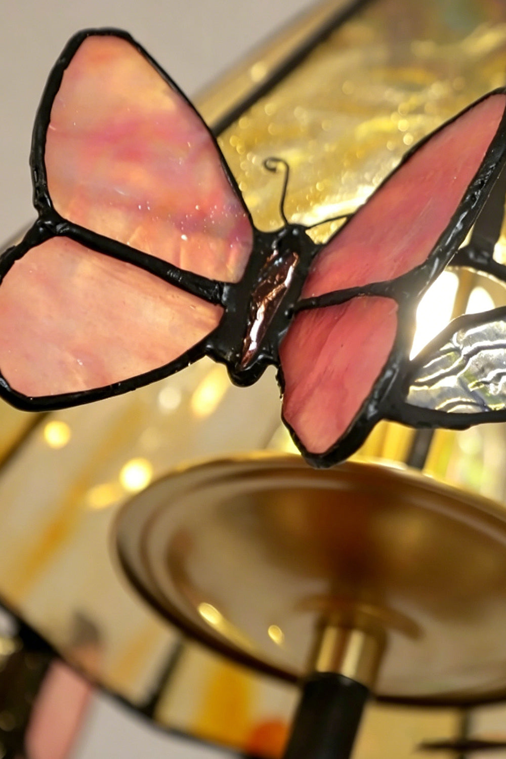 Seraphina Stained Glass Chandelier | Glass, Metal | Macro view of a translucent pink stained glass butterfly embellishment attached to the shade's rim | Detail shot | vexa lamps