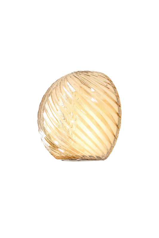 Silas Ribbed Glass Wall Sconce | Ribbed Glass, Metal | Isolated lit view of a modern organic pebble-shaped wall sconce featuring an amber-tinted swirled ribbed glass shade | White background | vexa lamps