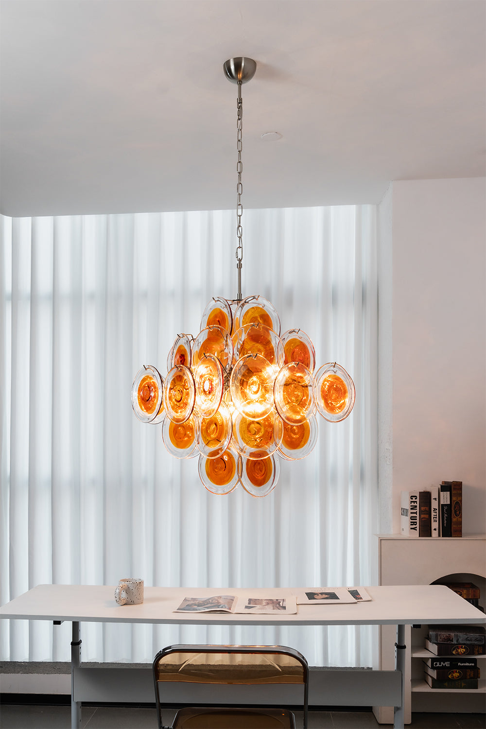 Modern tiered chandelier with amber glass discs | Metal, Glass | Installed in a minimalist work area with white furniture | vexa lamps