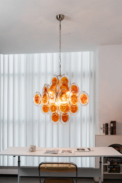 Modern tiered chandelier with amber glass discs | Metal, Glass | Installed in a minimalist work area with white furniture | vexa lamps