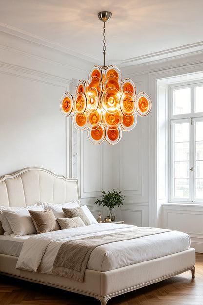 Warm-toned amber glass tiered chandelier | Metal, Glass | Installed in a neutral-toned bedroom over a large bed | vexa lamps