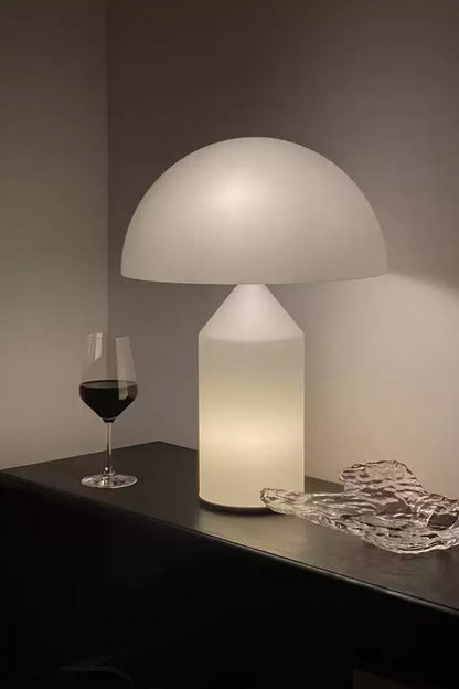 Solene Domed Glass Table Lamp | White Frosted Glass | Lit up on a dark shelf next to a glass of red wine creating a warm atmosphere | vexa lamps