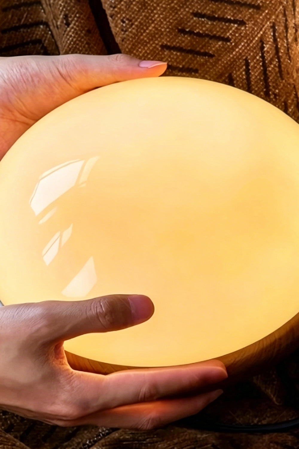 Soren Wood Grain Pendant Lamp | Wood, Glass, Metal | Close-up reference view of hands holding the fully illuminated glowing glossy glass diffuser bowl | Detail shot | vexa lamps