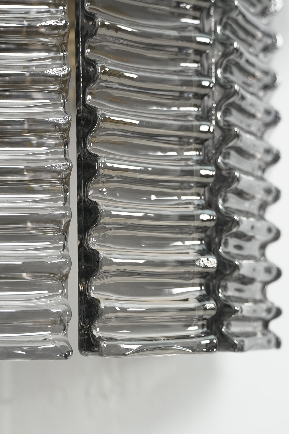 Close-up of the Sovereign Lattice Smoky Glass Wall Lamp showcasing ribbed smoky gray glass links.