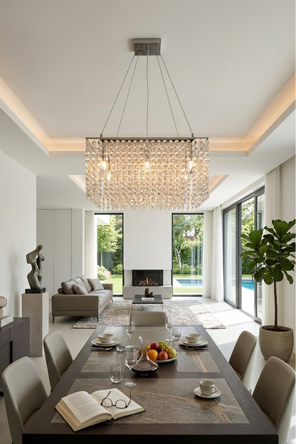 Sparkling crystal chandelier centered over a long dining table | Stainless Steel, Crystal | Elegant dining room with views of a garden and pool | vexa lamps