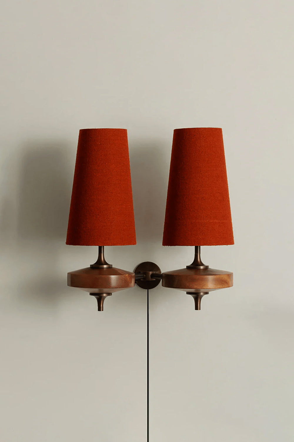 Spindle Walnut Wood Wall Sconce with dual orange fabric shades and antique brass accents, ideal for ambient lighting.