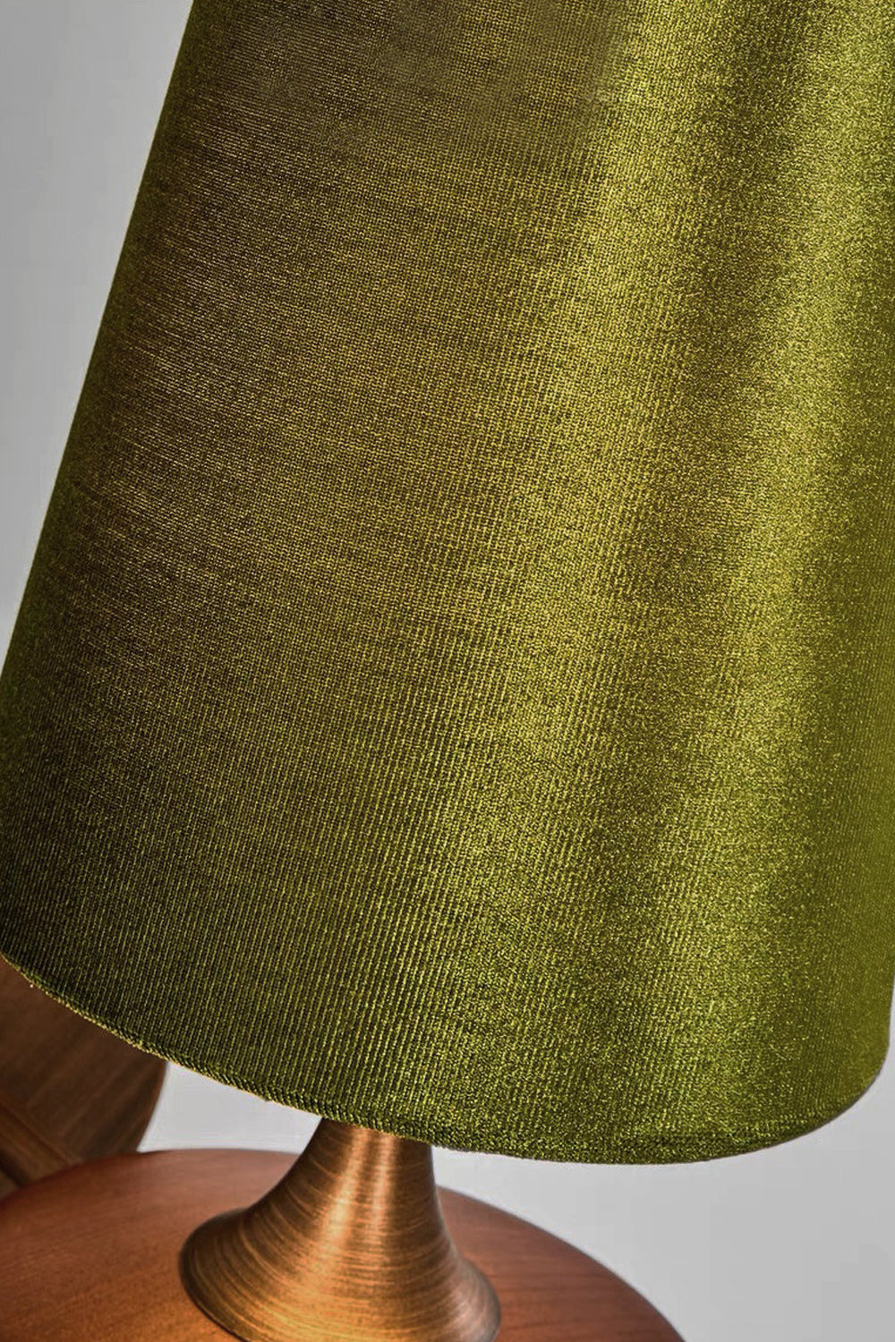 Close-up of a green fabric shade from the Spindle Walnut Wood Wall Sconce, featuring a walnut wood base and antique brass accents.