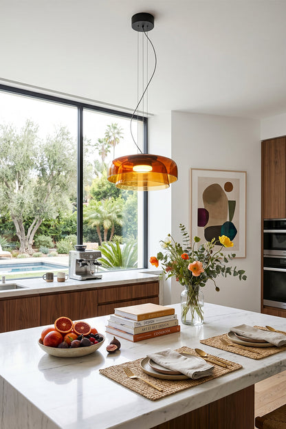 Stratum Layered Glass Pendant Light | Glass, Metal | Orange variant hanging as a warm centerpiece over a modern white kitchen island with flowers | vexa lamps