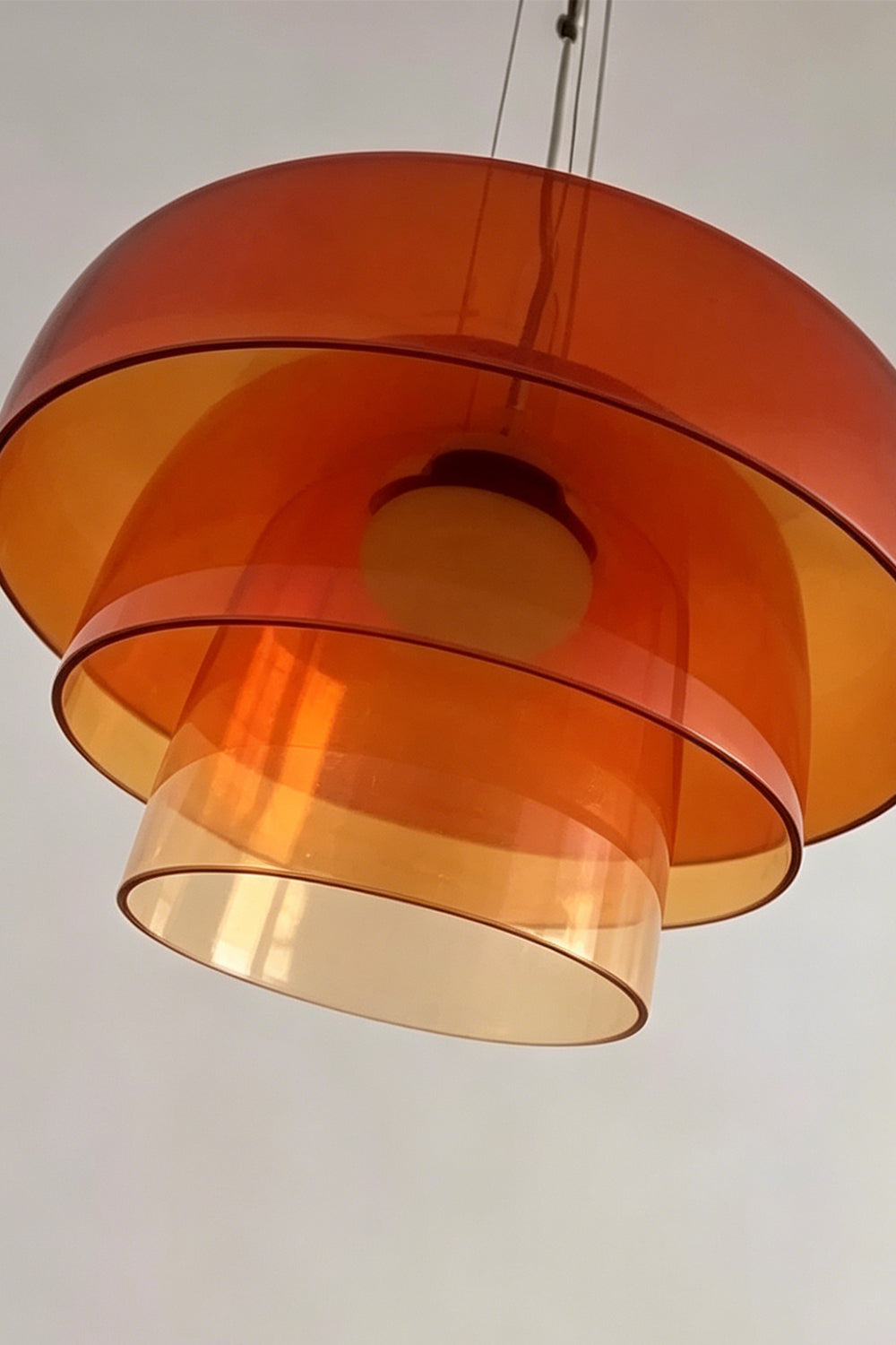 Stratum Layered Glass Pendant Light | Glass, Metal | Low-angle close-up highlighting the concentric tiered layers and smooth curved edges of the orange translucent glass | Detail shot | vexa lamps