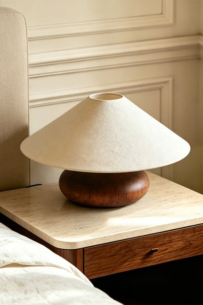 Sylvan Oval Walnut Table Lamp | Wood, Fabric, Metal | Placed on a marble-top wooden nightstand next to a bed with white sheets | vexa lamps