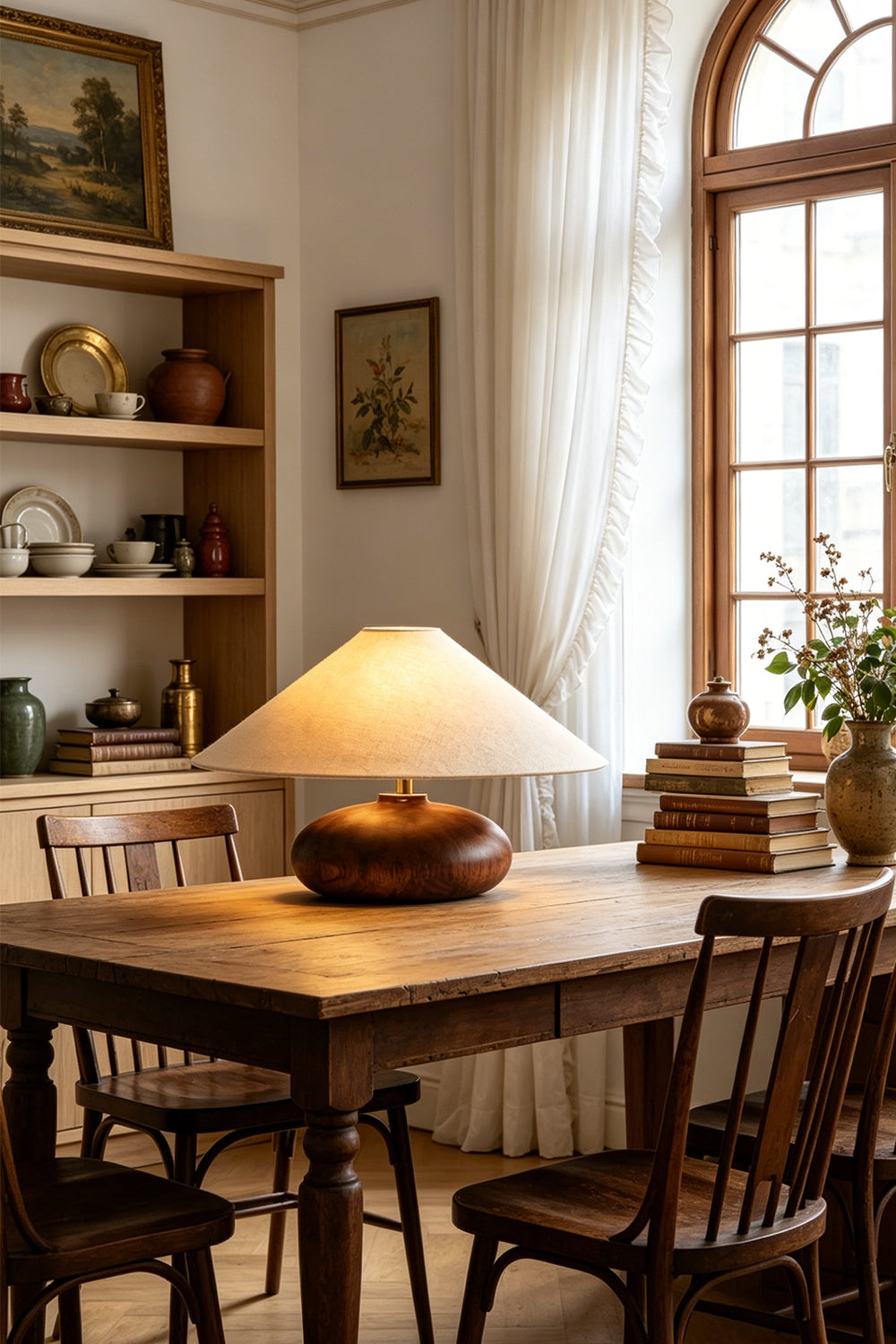Sylvan Oval Walnut Table Lamp | Wood, Fabric, Metal | Illuminating a rustic wooden dining table surrounded by classic wooden chairs | vexa lamps
