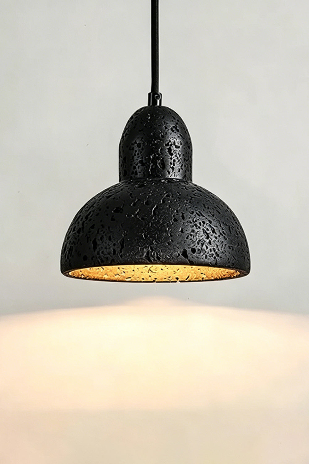 Lit Black Travertine Pendant Light | Black Travertine, Metal, Glass | Close-up showing warm upward and downward glow | vexa lamps