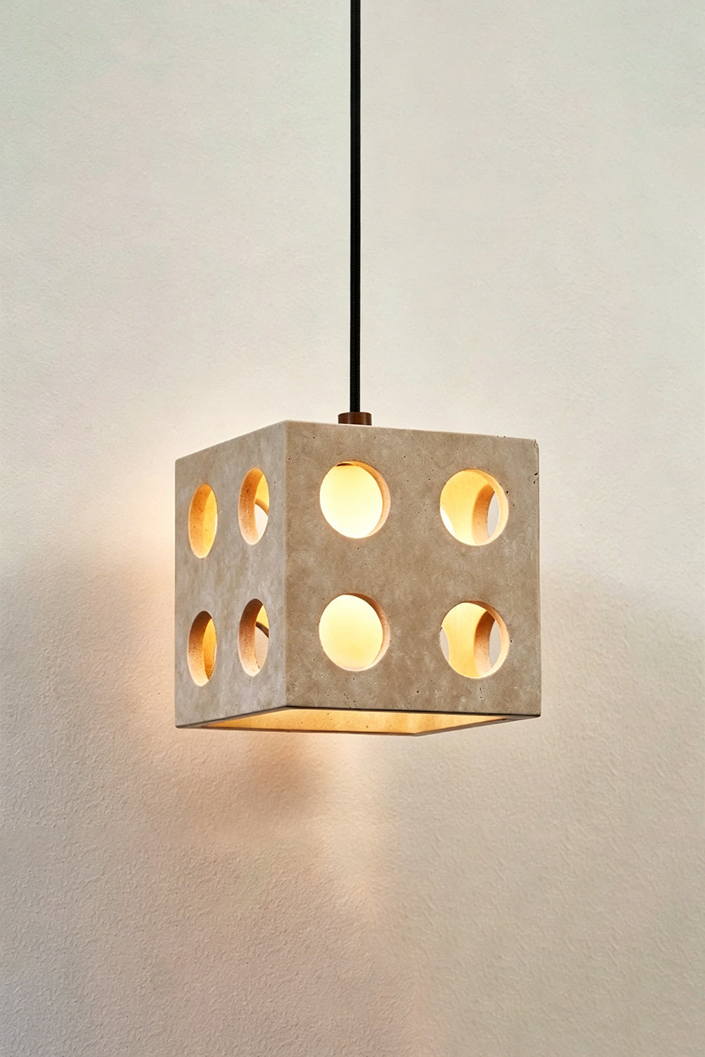 Terra Cube Travertine Pendant Light | Travertine, Metal | Lit product detail shot against textured wall | vexa lamps