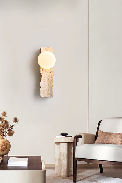 Sculptural stone wall lamp in minimalist interior | Yellow Travertine, Metal, Glass | Near a wooden armchair and decor | vexa lamps