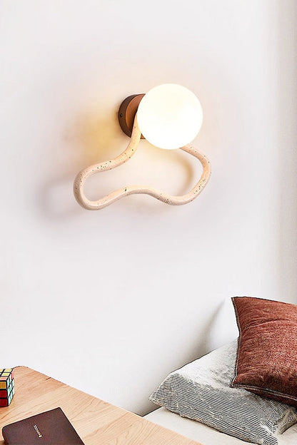 Lit travertine flow wall light in a modern bedroom | Travertine, Glass, Wood | Mounted above a desk near the bed | vexa lamps