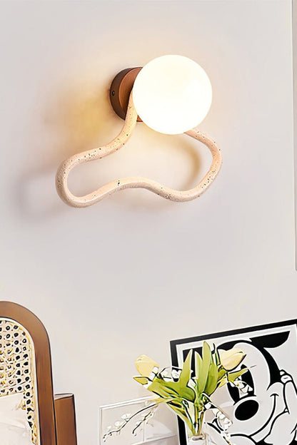 Lit travertine flow sconce on a white wall | Travertine, Glass, Wood | Detailed view of the wavy stone and glass globe | vexa lamps