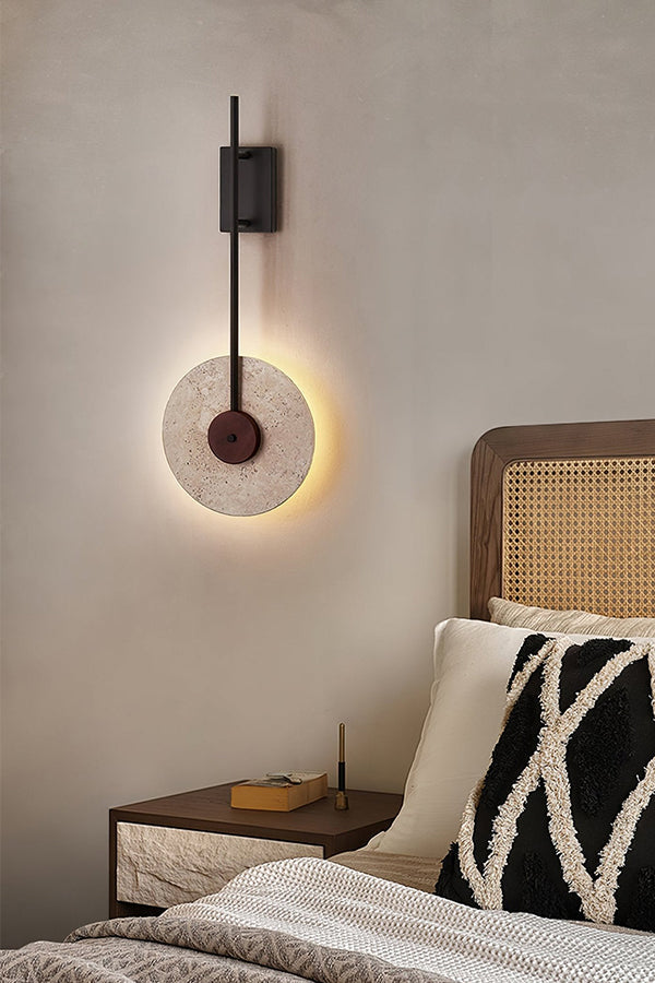 Travertine halo light in a warm bedroom setting | Travertine, Wood, Metal | Mounted near a rattan headboard and patterned pillows | vexa lamps