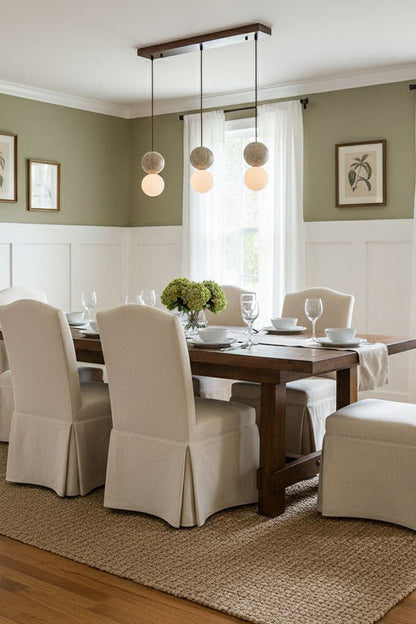 Linear travertine pendant light over dining table | Yellow Travertine, Glass | Installed in a formal dining room with slipcovered chairs | vexa lamps