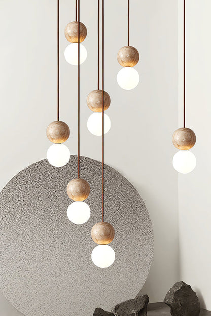 Cluster of travertine and glass pendant lights | Yellow Travertine, Glass | Detailed shot against a grey artistic backdrop | vexa lamps