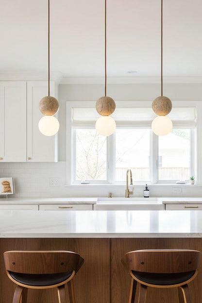 Linear travertine pendant light arrangement | Yellow Travertine, Glass | Hanging over a white kitchen island with wooden stools | vexa lamps