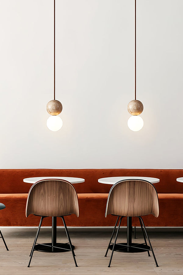 Pair of travertine stone pendants over a booth | Yellow Travertine, Glass | Installed in a restaurant or dining nook | vexa lamps