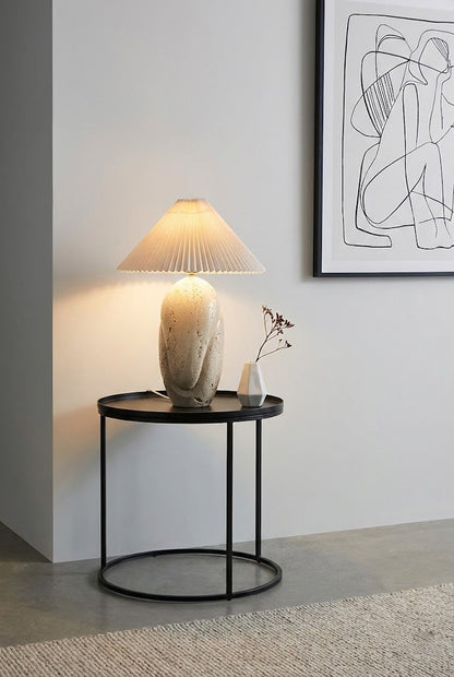 Sculptural travertine lamp on metal stand | Travertine, Fabric | On a black round side table against a grey wall | vexa lamps
