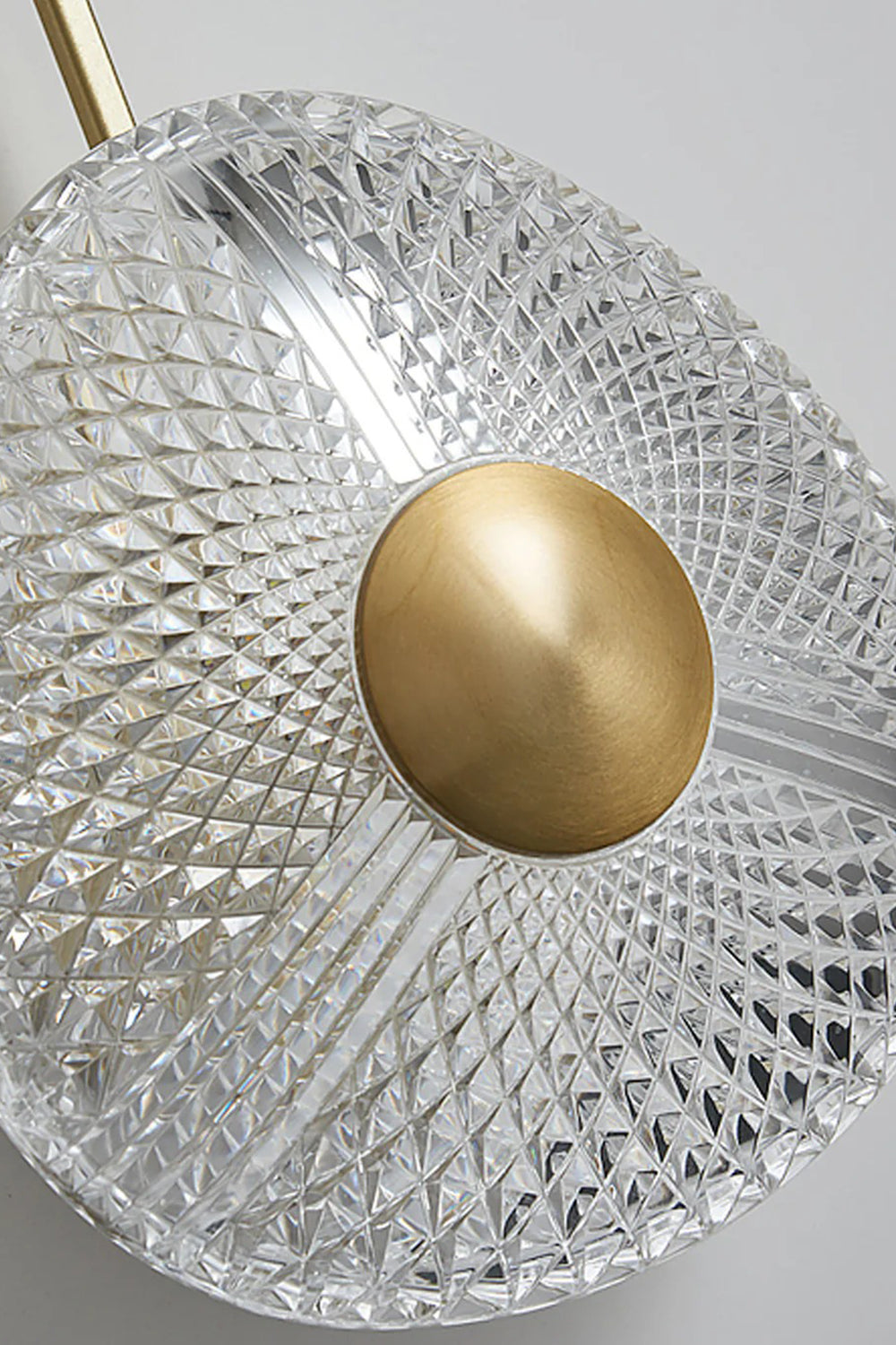 Vara Aura Woven Acrylic Wall Lamp | Woven Acrylic, Brass | Close-up shot focusing on the intricate woven pattern of the clear acrylic shade and central brass disc | vexa lamps