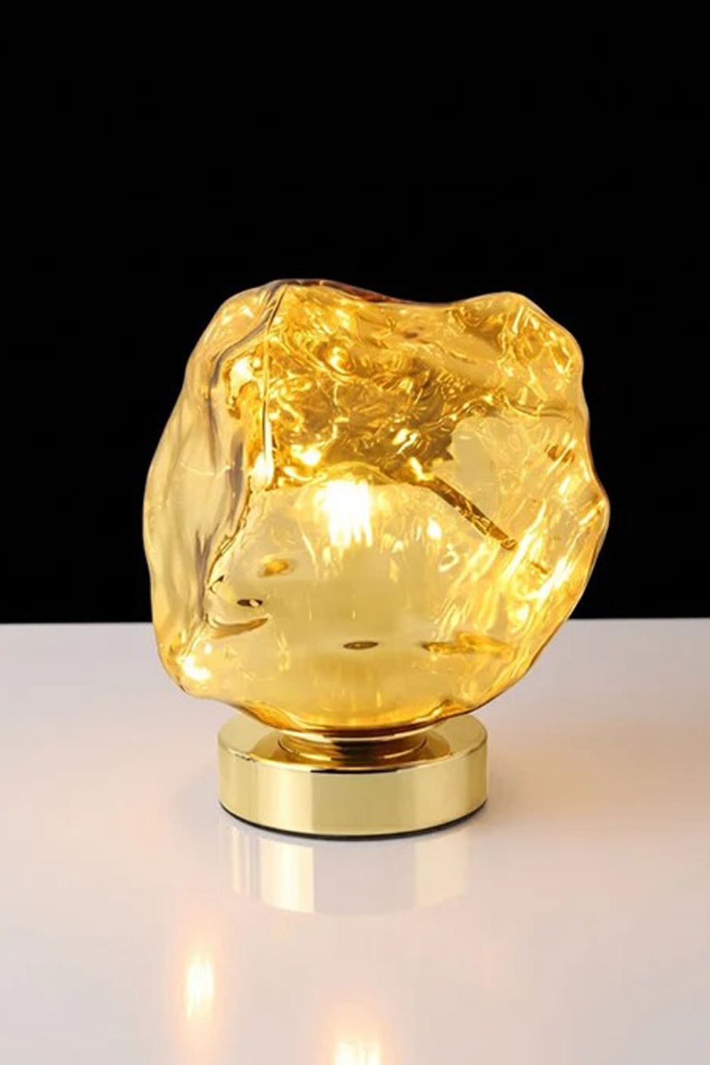 Vega Molten Metal Table Lamp with a shimmering golden base and organic, fluid shape, providing a stylish light source.