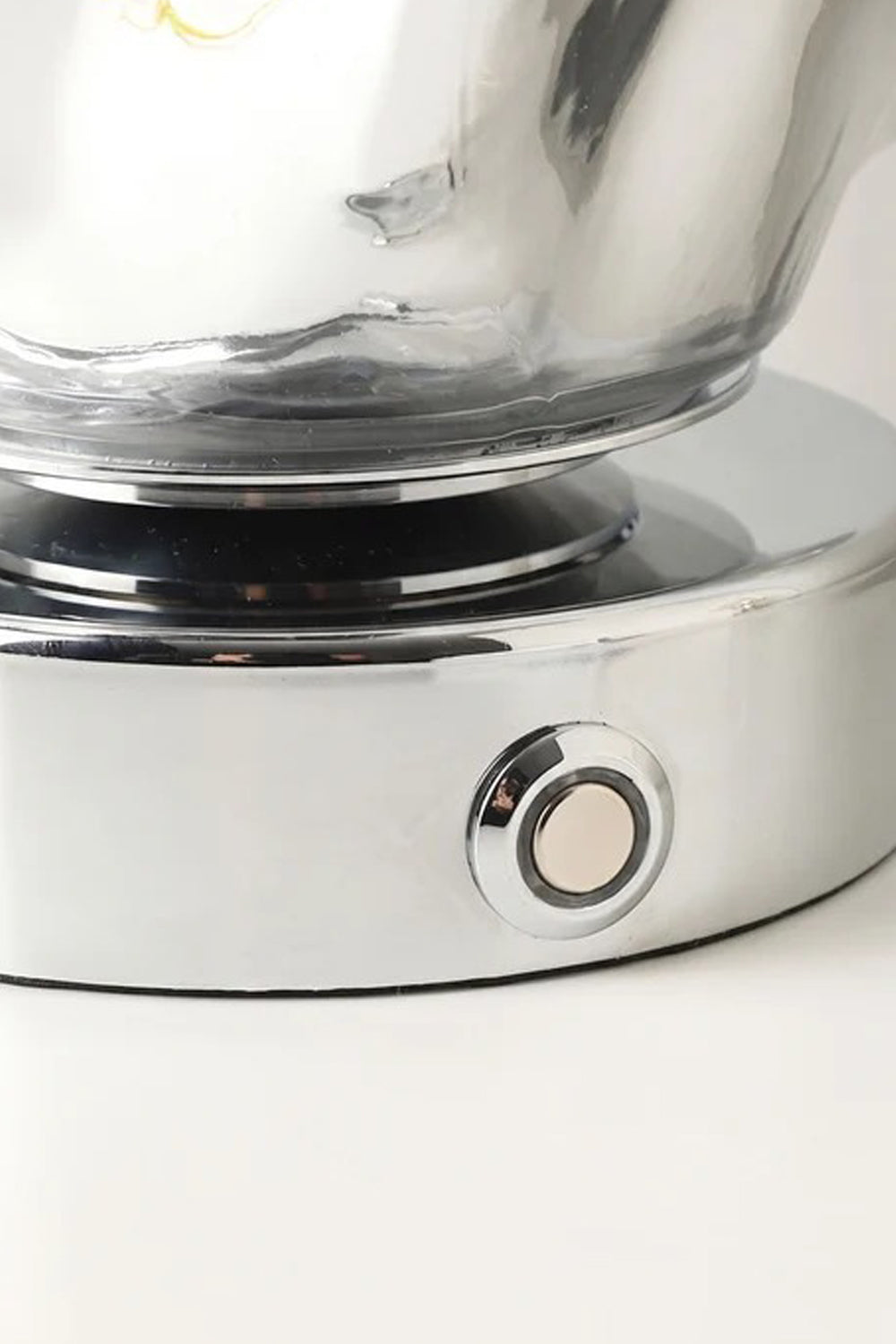 Close-up of the base and switch of the Vega Molten Metal Table Lamp showcasing its reflective surface.