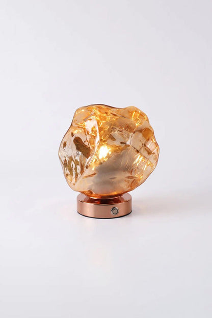 Vega Molten Metal Table Lamp with a sculptural, organic design and a warm glow, perfect for any space.