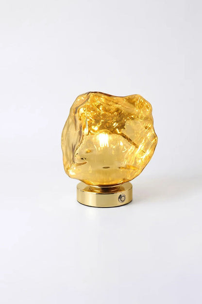 Vega Molten Metal Table Lamp with gold glass base reflecting light beautifully.
