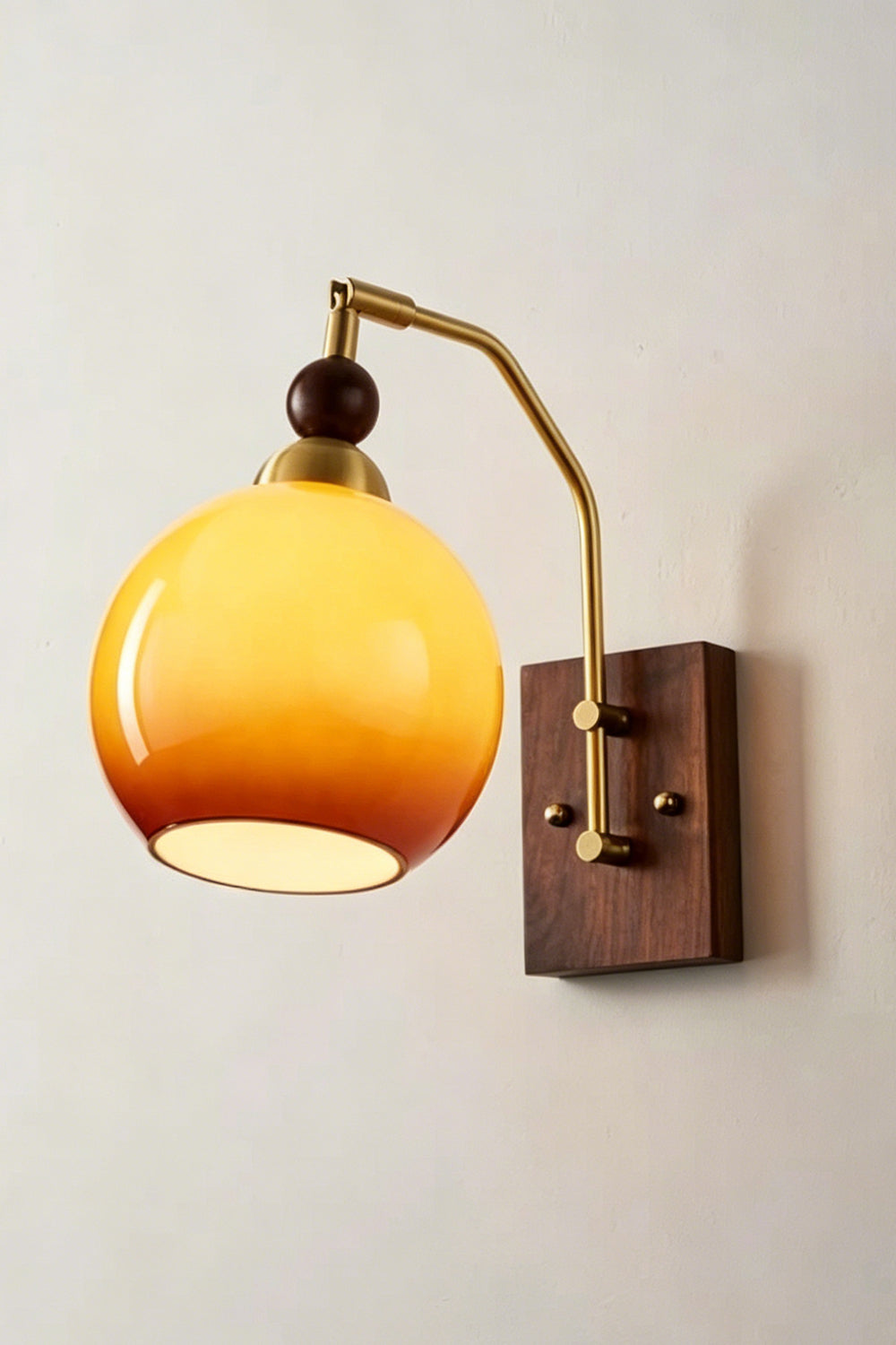 Vesper Caramel Gradient Wall Lamp | Glass, Metal, Wood | Angled view of the fully illuminated glass sconce radiating a soft golden glow against a plain white wall | vexa lamps