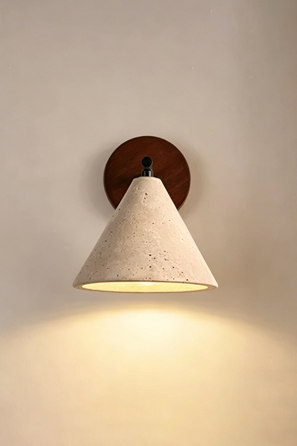 Vesper Cone Travertine Wall Light | Travertine, Wood | Lit sconce on neutral wall providing warm downlight | vexa lamps