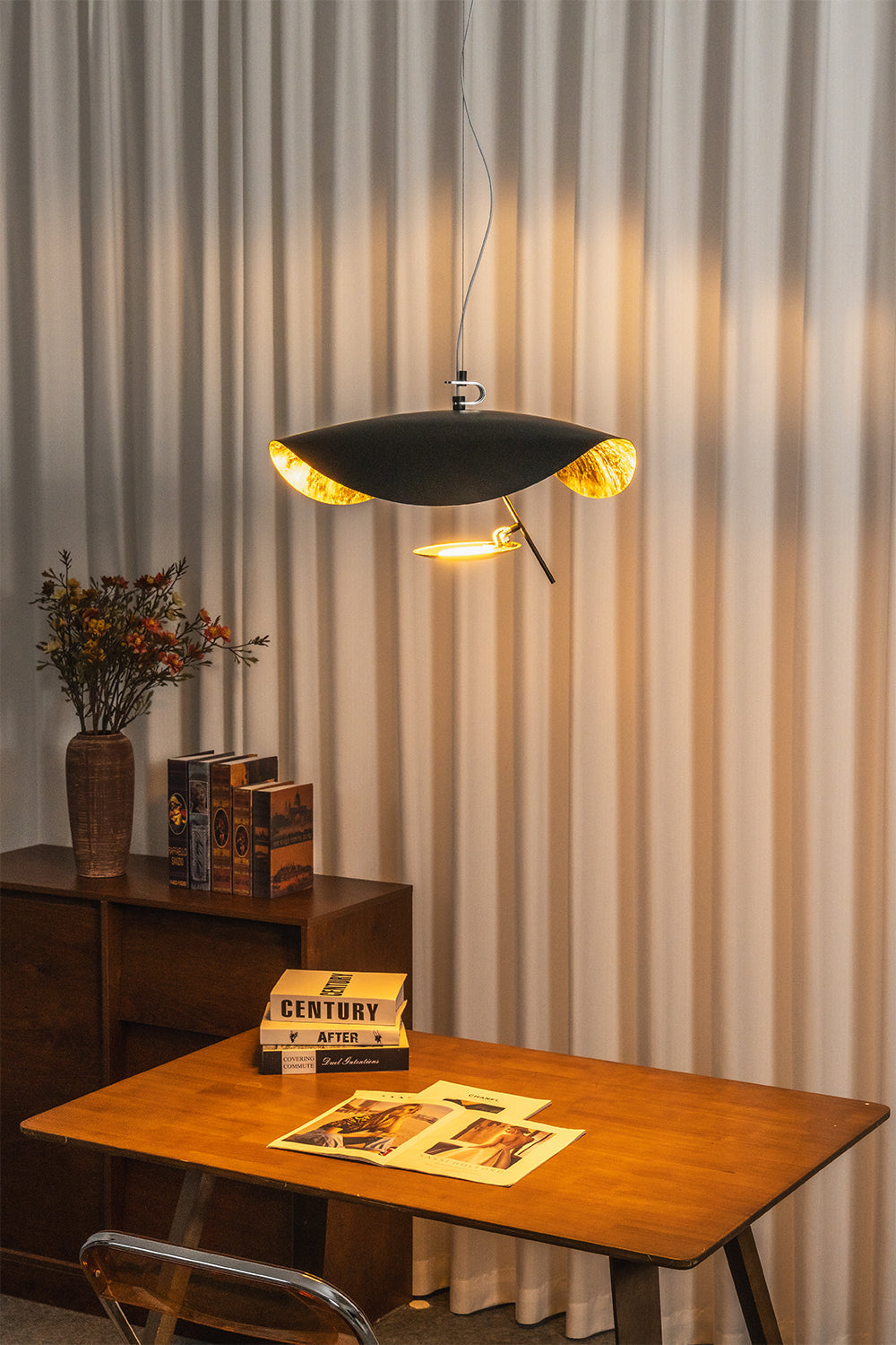 Voluta Horizon Metal Pendant Light | Metal | Fully lit black pendant casting a warm golden glow onto vertical blinds over a wooden table | vexa lamps