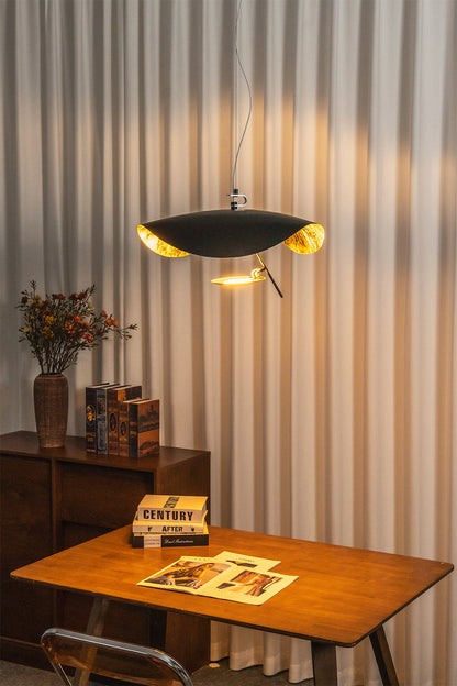 Voluta Horizon Metal Pendant Light | Metal | Fully lit black pendant casting a warm golden glow onto vertical blinds over a wooden table | vexa lamps