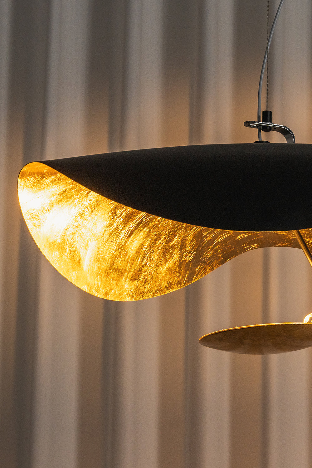 Voluta Horizon Metal Pendant Light | Metal | Close-up profile view of the black outer shell and the radiant textured gold foil inner lining | Detail shot | vexa lamps