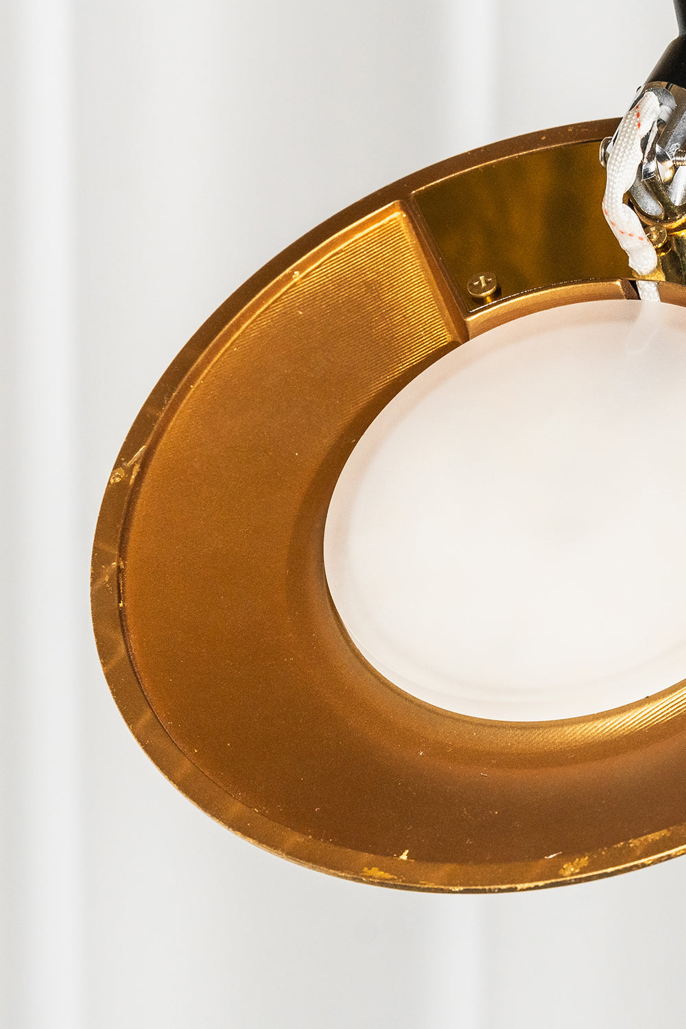 Voluta Horizon Metal Pendant Light | Metal | Close-up of the glowing circular white diffuser set within a polished gold metal ring | Detail shot | vexa lamps