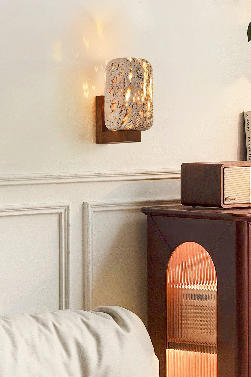 Wabi-Sabi stone wall light on a classic molded wall | Travertine, Wood | Interior scene near a dark wooden side table | vexa lamps