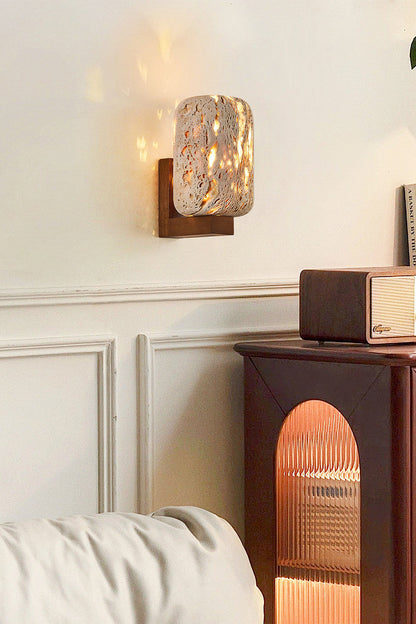 Wabi-Sabi stone wall light on a classic molded wall | Travertine, Wood | Interior scene near a dark wooden side table | vexa lamps