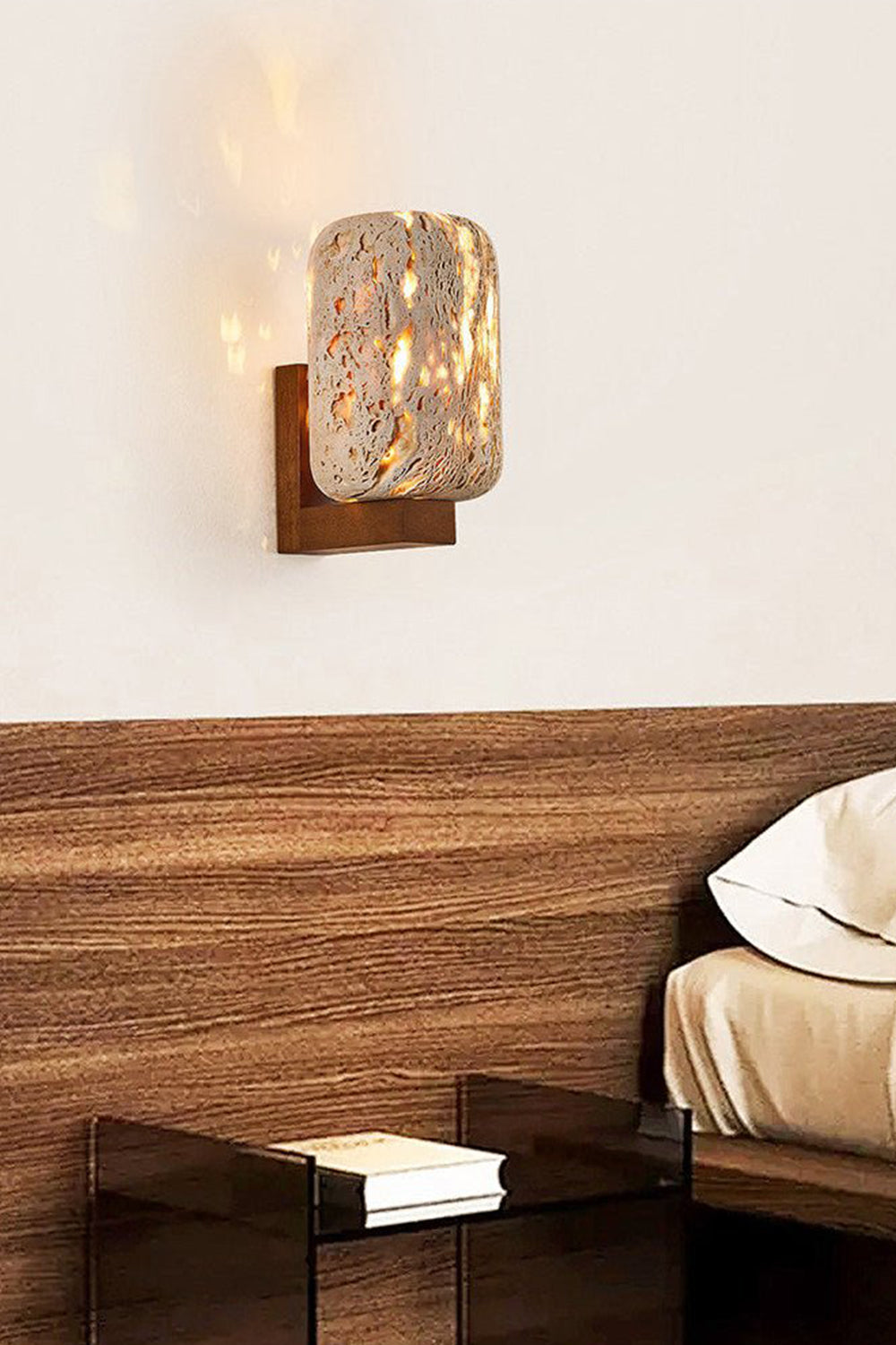 Travertine cylinder sconce providing warm glow | Travertine, Wood | Mounted above a wooden headboard in a minimalist bedroom | vexa lamps