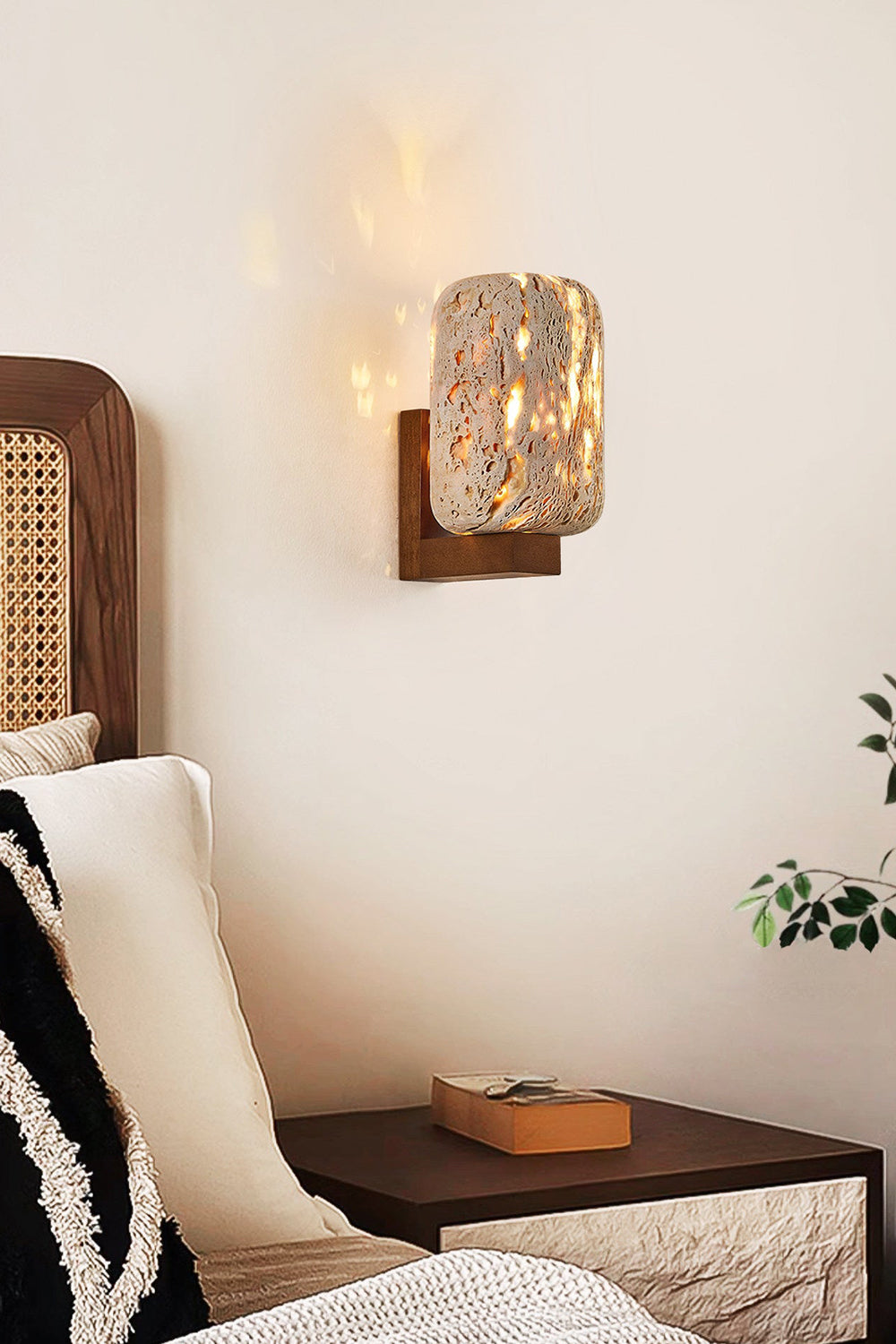 Lit cylinder stone wall sconce | Travertine, Wood | Positioned next to a rattan bed and dark nightstand | vexa lamps